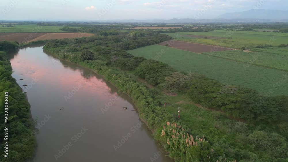 Aerial View of Cauca River At Sunset with Water Reflection. Sugar Cane Crops. Pull Back Shot. Valle del Cauca. Colombia Aerial View of Cauca River At Sunset with Water Reflection. Sugar Cane Crops. Pull Back Shot. Valle del Cauca. Colombia
