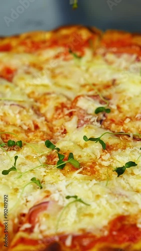 Cook decorates ready pizza. Chef's hand in glove is sprinking fresh green sprouts on a baked pizza in a restaurant. Close-up. Vertical video photo