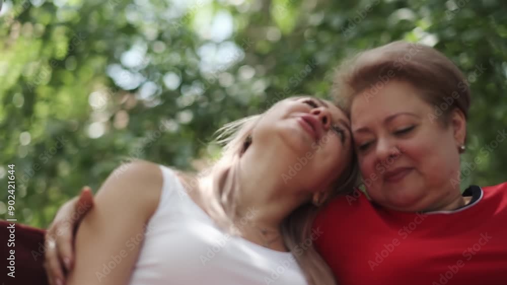 An adult mother with a young daughter swinging on a swing in the garden next to her house. Hugging, talking and laughing. An adult mother with a young daughter swinging on a swing in the garden next to her house. Hugging, talking and laughing.