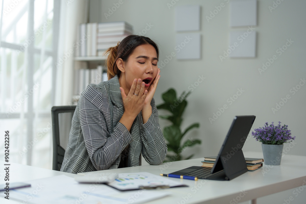 Asian woman, independent businesswoman, feeling stressed, achy, and sleepy while working on a laptop. Tired Asian businesswoman has a headache at the office Feeling sick at work. Asian woman, independent businesswoman, feeling stressed, achy, and sleepy while working on a laptop. Tired Asian businesswoman has a headache at the office Feeling sick at work.