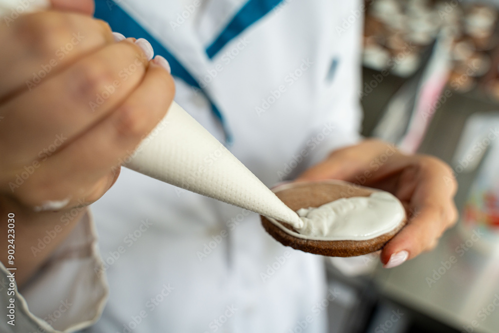 A pastry chef decorates pastries or cookies with a pastry bag with white icing. Small confectionery shop, bakery, handmade. A pastry chef decorates pastries or cookies with a pastry bag with white icing. Small confectionery shop, bakery, handmade.
