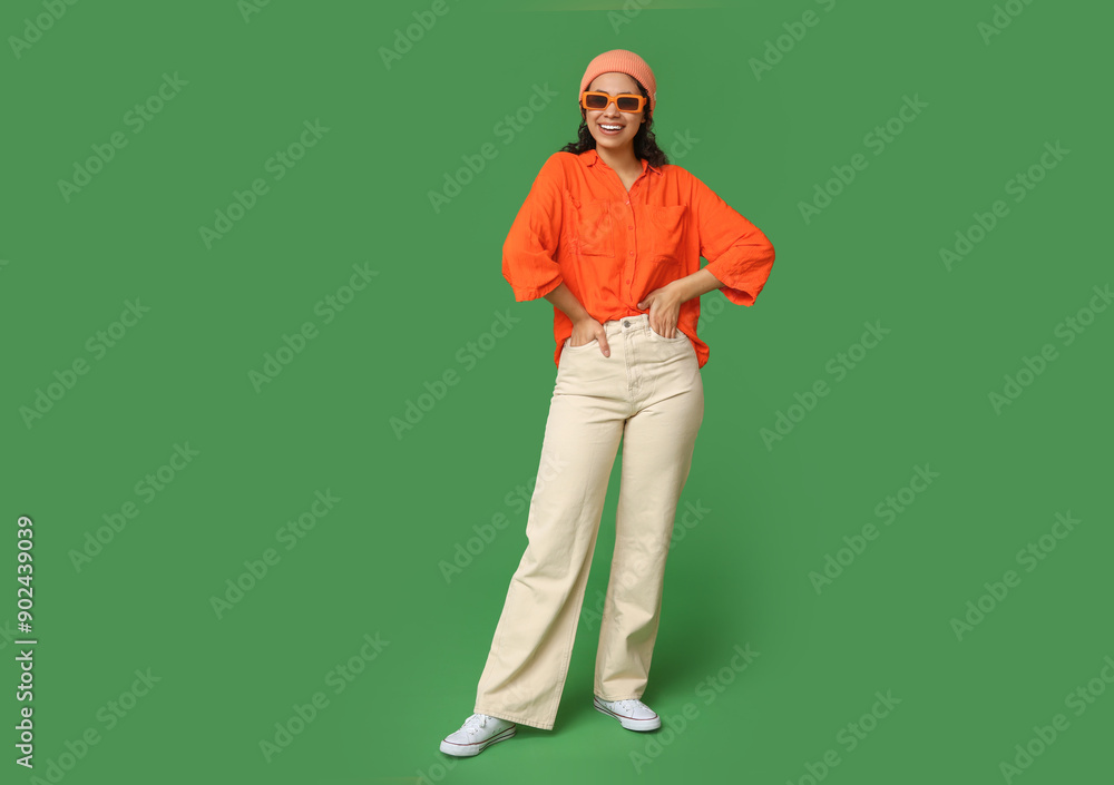 Cool African-American woman wearing hat and sunglasses on green background Cool African-American woman wearing hat and sunglasses on green background
