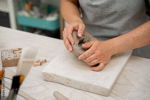 Wedging the clay before starting making a pottery project to create proper consistency. Removing air bubbles from clay before modeling to avoid the ruination of a ceramic product. © Rabizo Anatolii