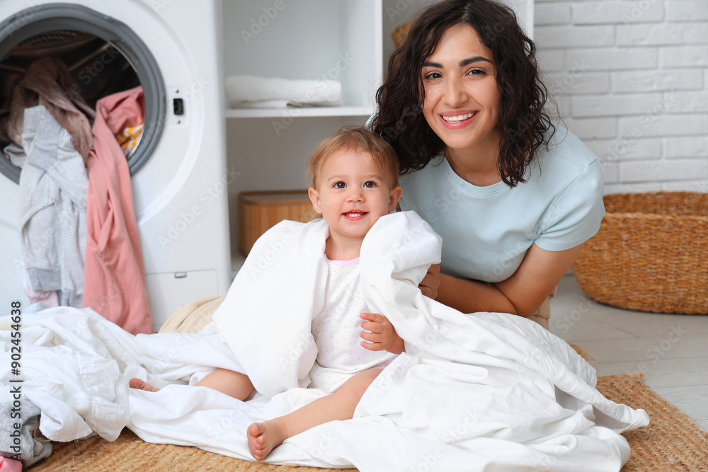 Young mother with her cute little baby doing laundry in bathroom Young mother with her cute little baby doing laundry in bathroom