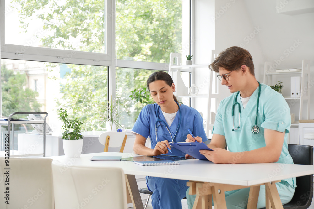 Obraz premium Young doctors studying x-ray image at table in clinic