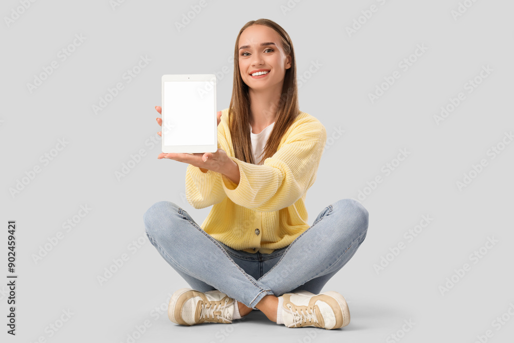 Young woman with blank tablet computer sitting on light background Young woman with blank tablet computer sitting on light background
