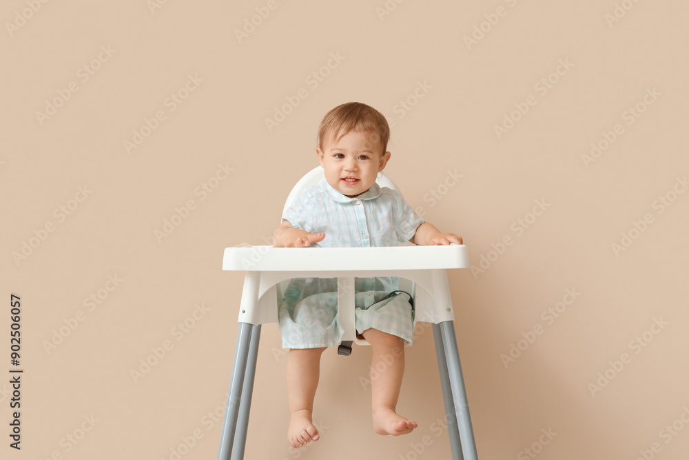 Cute little baby in high chair on beige background Cute little baby in high chair on beige background