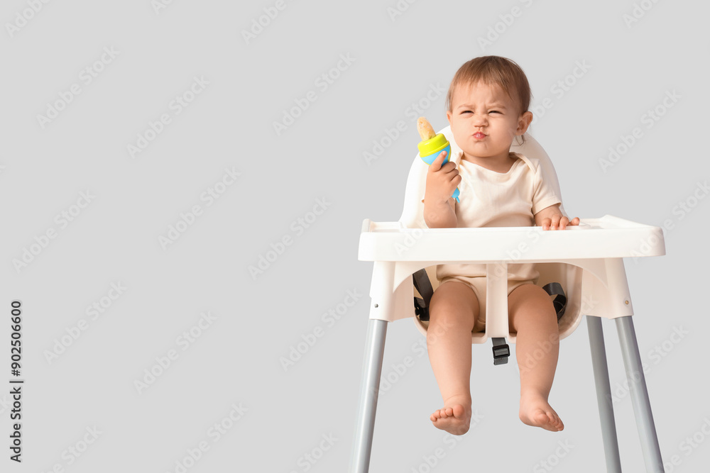 Cute little baby with nibbler in high chair on light background Cute little baby with nibbler in high chair on light background