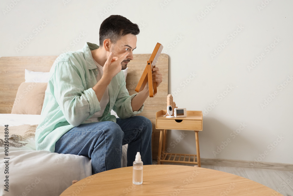 Young man with mirror putting in contact lenses at home Young man with mirror putting in contact lenses at home