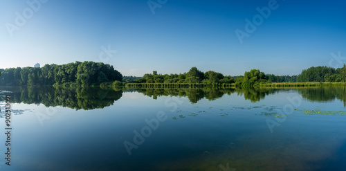 Reflection of trees in the lake. Panoramic view of the banks of the river bay