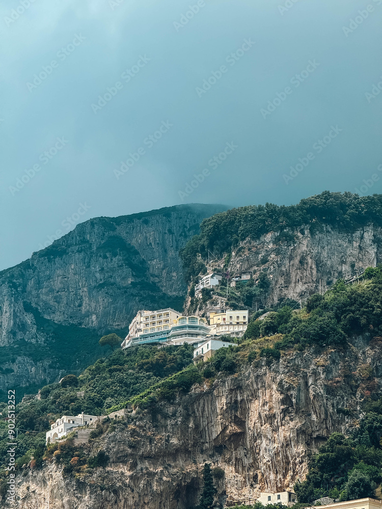 Obraz premium A mountain with a small house on top of it. The house is surrounded by trees and the sky is cloudy