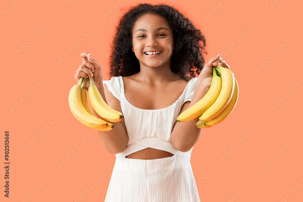 Little African-American girl with bananas on orange background Little African-American girl with bananas on orange background