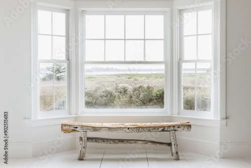 Rustic wooden bench in front of a bay window with a view of a lake and grassy field