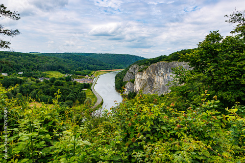 Panoramic aerial view of valley with Meuse river, Freyr Castle and huge Freyr Rocks rock formation, green leafed trees covering valley, cloudy summer day in Namur province, Wallonia, Belgium