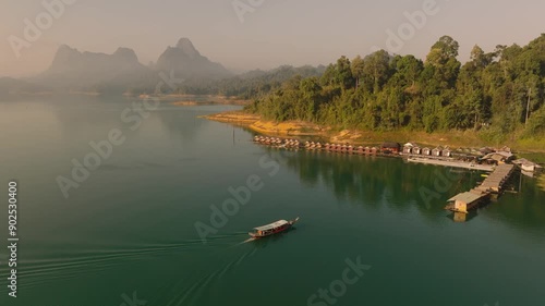 4K aerial drone footage of boat comming to floating rooms in Kao Sok National Park during a sunrise, Lake and Mountains,Thailand, Asia photo