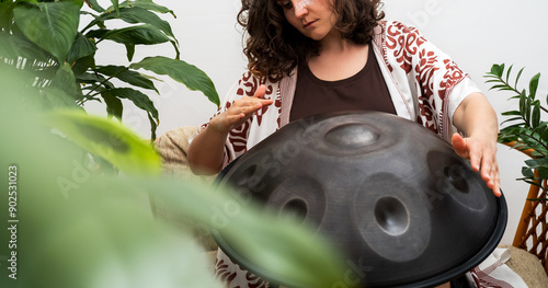 Woman plays relaxing music with hang drum.