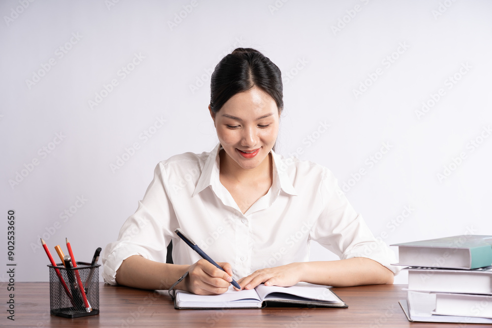 Young female businessman sitting at desk on white background Young female businessman sitting at desk on white background