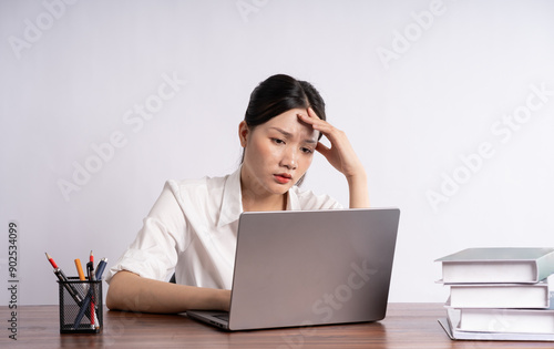 Young female businessman sitting at desk on white background