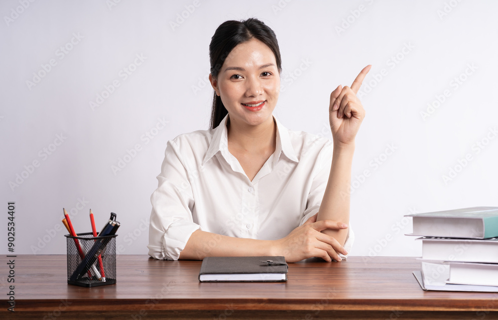 Young female businessman sitting at desk on white background Young female businessman sitting at desk on white background