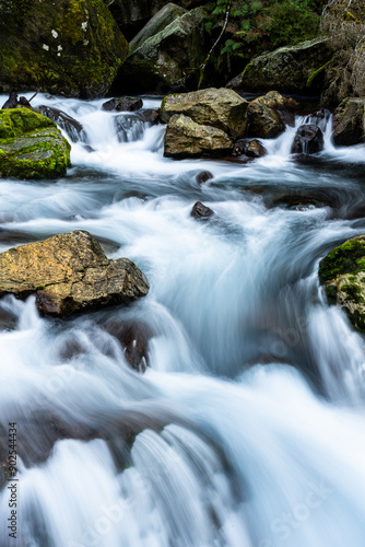 waterfall in the mountains with running water and moss on the rocks in the water