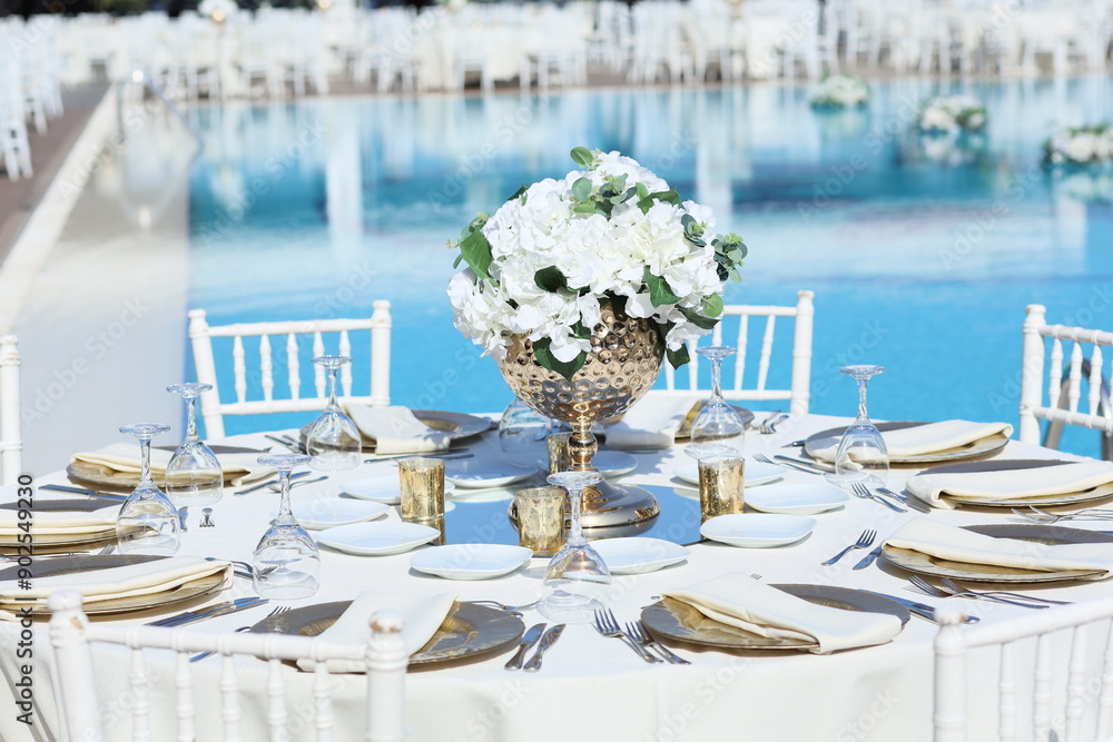 Romantic poolside wedding setup with white chairs and white linens