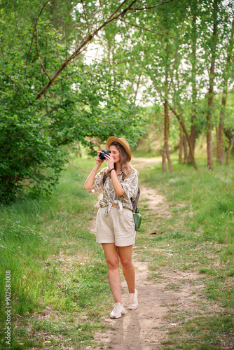 Young woman enjoying nature while taking photographs on a lush forest path during daylight