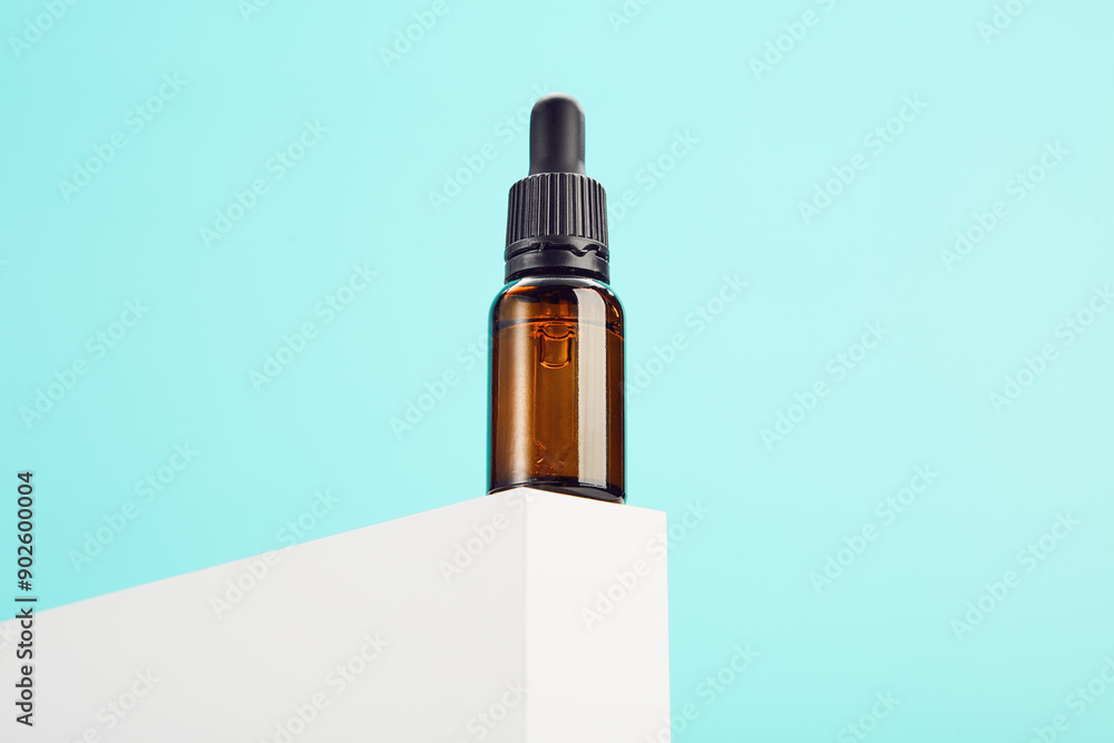 Opened glass dropper container is on white shape on blue. Opened glass dropper container is on white shape on blue.