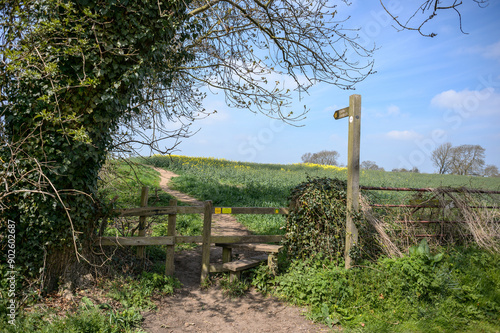 A wooden footpath sign and stile in rural North Yorkshire, UK.