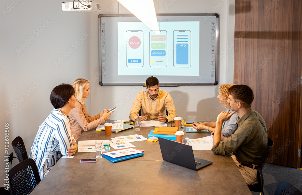 Group of business people sitting in a meeting room discussing a design for a smartphone application. Group of business people sitting in a meeting room discussing a design for a smartphone application.