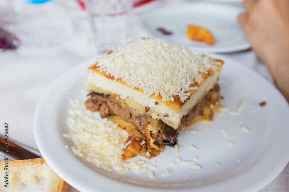 Traditional Greek moussaka served on a rustic restaurant table, showcasing rich, layered Mediterranean flavors Traditional Greek moussaka served on a rustic restaurant table, showcasing rich, layered Mediterranean flavors