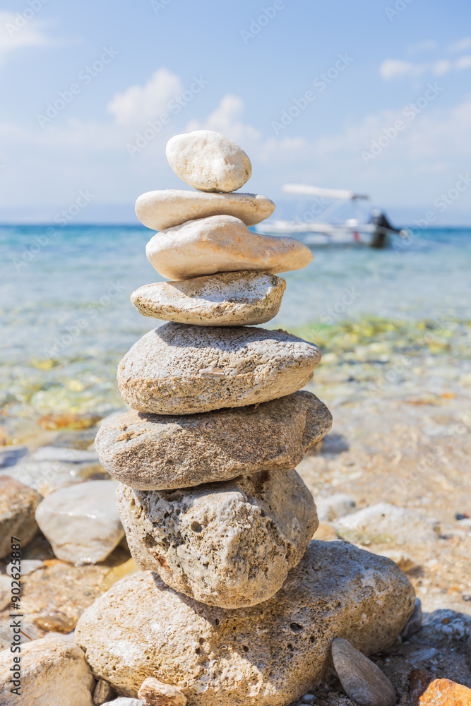 Tranquil beach scene with stacked stones, clear water, and a boat in the background, perfect for relaxation and balance. Tranquil beach scene with stacked stones, clear water, and a boat in the background, perfect for relaxation and balance.