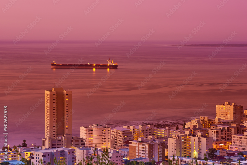 Fototapeta premium Cityscape, sunset and ocean or urban landscape with buildings, boat and sea or outdoor. Development, skyline and port or dock for shipping, cargo and tourism or travel for architecture or hospitality