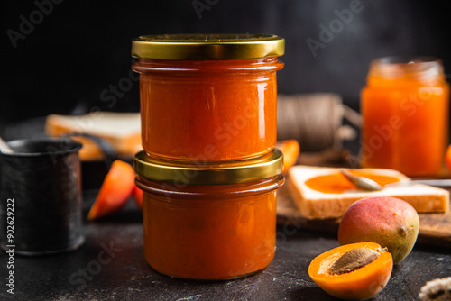 Ripe apricot jam in a glass jar on the table.