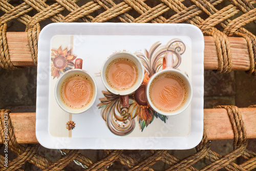 Wafer and chocolate drink on white cup. Dessert time concept. Isolated background in white, milk tea three cup, milk tea cup in dish, Hot milk tea in a white cup on wooden table blurred background,  photo