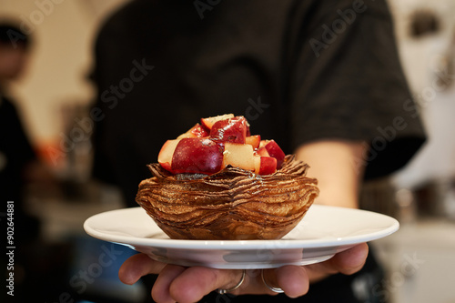 Close-up of pastry topped with fresh fruit held by waiter photo