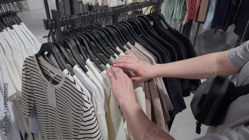 Men's clothing store, man browsing clothes racks. Young shopper in store trying on new clothes in mall. Men's clothing. Wardrobe. Sale, shopping, fashion, style