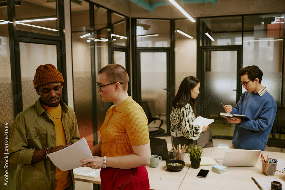 Obraz premium Multi-ethnic group of young men and women wearing stylish casual clothes working in pairs in modern office