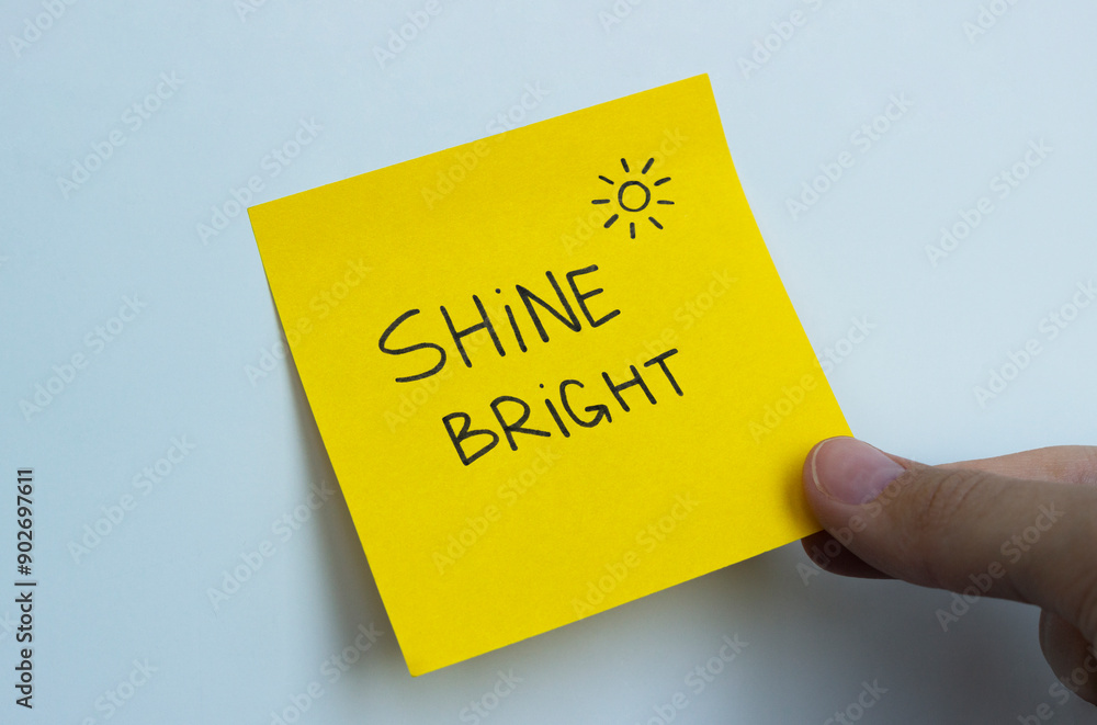 A yellow post-it note that says 'shine bright' with a symbol of the sun in the corner A yellow post-it note that says 'shine bright' with a symbol of the sun in the corner