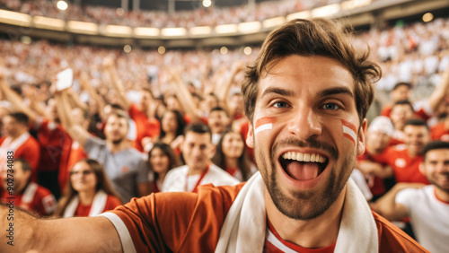 A fan takes a selfie against the background of a blurred crowd at the stadium, the crowd is fans of a certain team