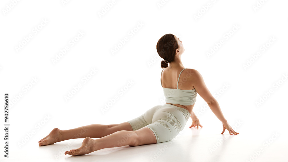 Obraz premium Woman during yoga session, emphasizing spine flexibility and strength, enhancing relaxation and overall wellness against white background. Concept of beauty, mindfulness and balance, concentration. Ad