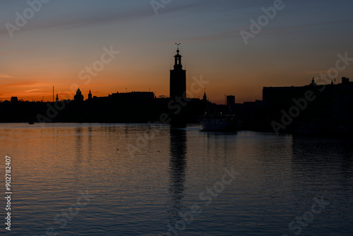 Photography Panoramic view of Stockholm City hall at sunset with orange sky and calm water reflection