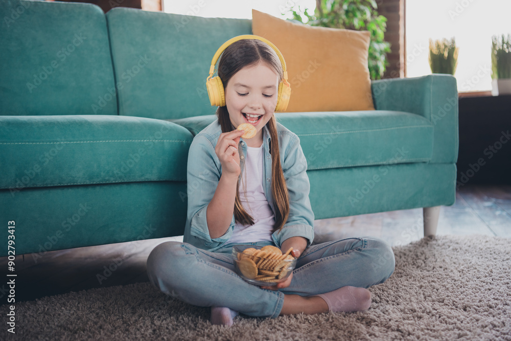 Full length portrait of cute little girl headphones eat cookie wear shirt loft interior modern flat indoors Full length portrait of cute little girl headphones eat cookie wear shirt loft interior modern flat indoors