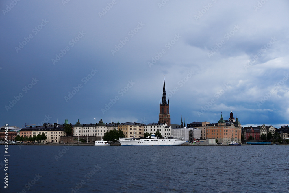 Obraz premium View of a city by the river against cloudy sky