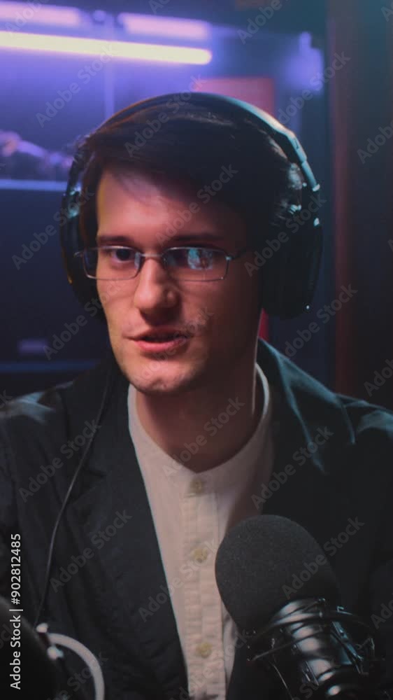 A young guy DJ or presenter with headphones on an interview with an old woman podcast, communicates with a guest. Streaming on a radio show in a broadcast studio. Influence, journalist man A young guy DJ or presenter with headphones on an interview with an old woman podcast, communicates with a guest. Streaming on a radio show in a broadcast studio. Influence, journalist man