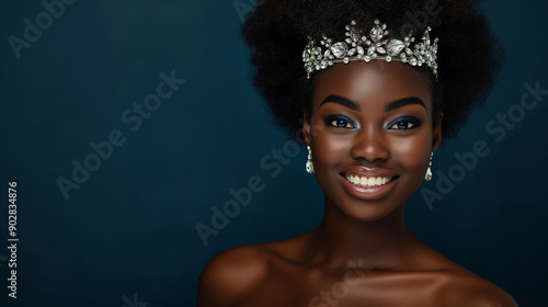 Beautiful smiling woman wearing tiara, earrings, necklace isolated on dark navy background in studio