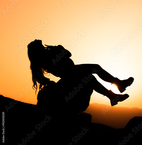 beautiful silhouette view of girl sitting on a rock front of sunset 