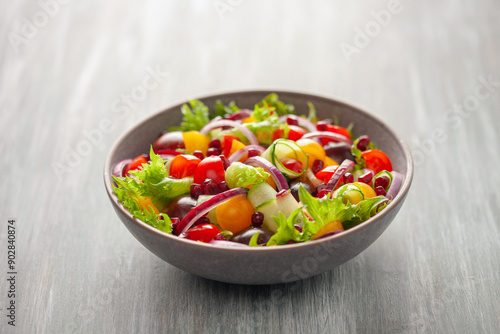 Easy vegetarian salad of fresh cucumber, tomato, sweet pepper, onion with pomegranate seeds. Healthy food.