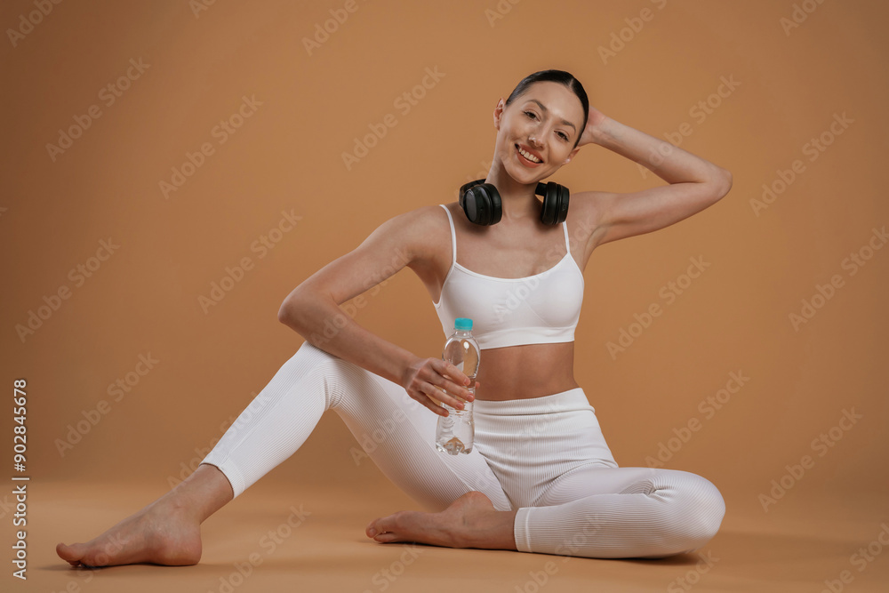 Obraz premium Black headphones on the neck. Beautiful fitness woman is in the studio