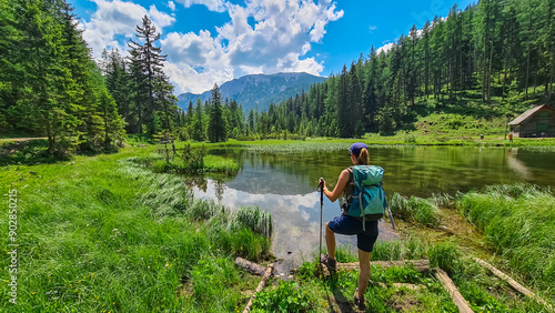 Hiker woman with scenic view of alpine lake Josersee surrounded by forest in Hochschwab mountains, Styria, Austria. Wanderlust in wilderness of untamed Austrian Alps, Europe. Idyllic hiking atmosphere photo