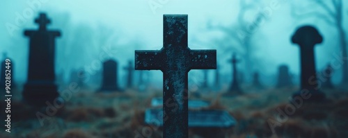 Atmospheric and moody image of a graveyard or cemetery with tall tombstones and crosses shrouded in thick fog creating a haunting and eerie scene with deep depth of field